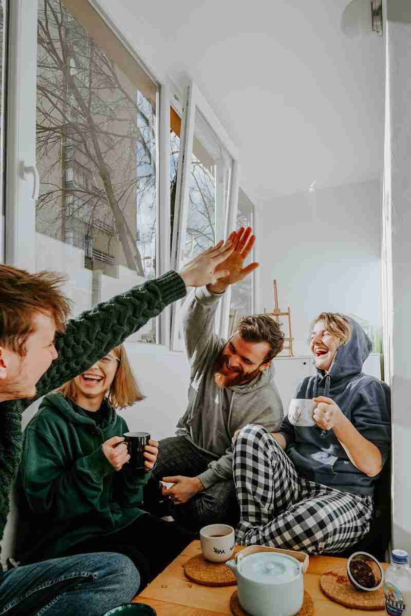 four friends laughing and high fiving over coffee